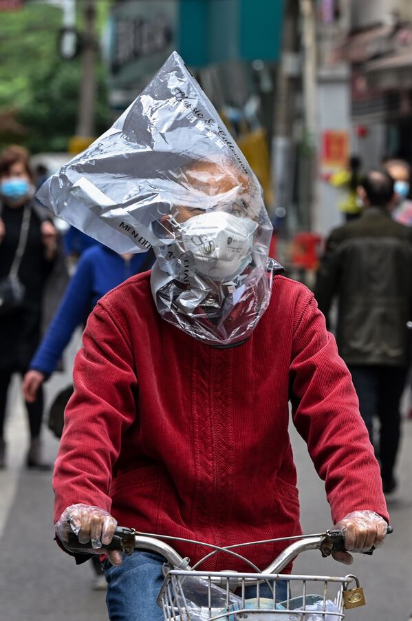 Велосипедист в защитной маске и с пластиковым пакетом на голове на одной из улиц Уханя в Китае - Sputnik Грузия