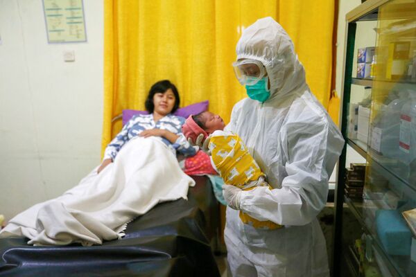  Медсестра в защитном костюме держит новорожденного в родильном отделении в Депоке, недалеко от Джакарты - Sputnik Грузия