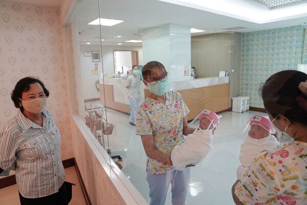 Медсестры в защитных масках держат новорожденных в защитных лицевых щитках в целях профилактики коронавируса в больнице в Таиланде - Sputnik Грузия