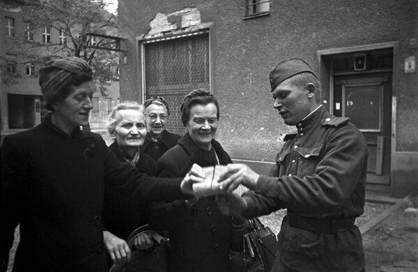 Советский солдат раздает хлеб женщинам в Берлине, 7 мая 1945 года - Sputnik Грузия