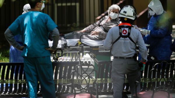 Медицинские работники несут женщину на носилках для перевода в больницу. Ситуация в связи с коронавирусом в мире - Sputnik Грузия