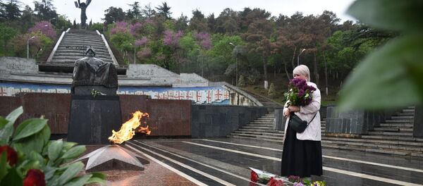 День Победы 9 мая 2020 года в парке Ваке. Женщина с цветами у Вечного огня и у Могилы Неизвестного Солдата День Победы 9 мая 2020 года в парке Ваке. Женщина с цветами у Вечного огня и у Могилы Неизвестного Солдата - Sputnik Грузия