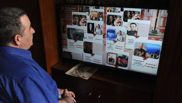 Мужчина смотрит онлайн-трансляцию акции Бессмертный полк - Sputnik Грузия