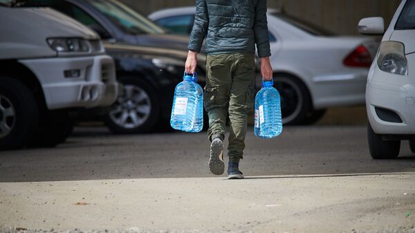 Мужчина несет канистры с водой к себе домой - Sputnik Грузия