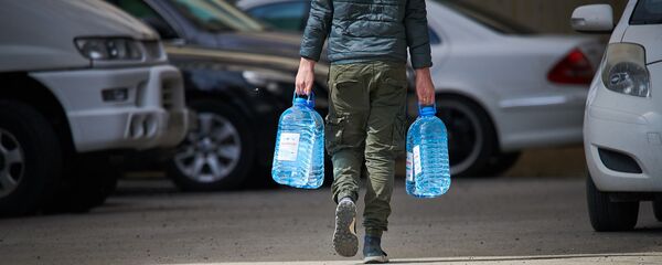 Мужчина несет канистры с водой к себе домой Мужчина несет канистры с водой к себе домой - Sputnik Грузия