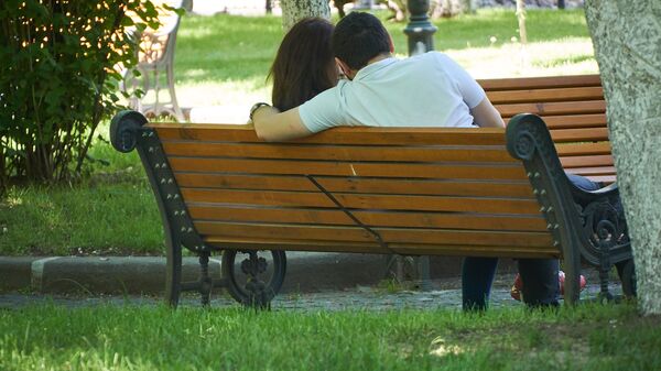Влюбленные сидят на скамейке в парке в солнечный день в мае. Александровский сад - Sputnik Грузия