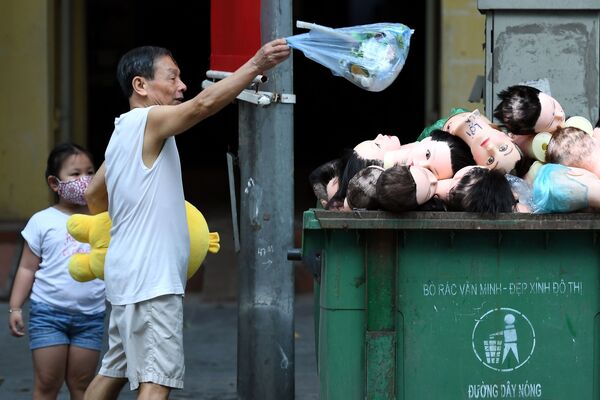 Мужчина бросает мусор в мусорный бак с головами манекенов во Вьетнаме - Sputnik Грузия