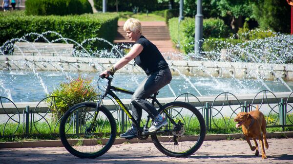 Весна в столице Грузии. Парк Ваке. Женщина едет на велосипеде - за ней бежит собака - Sputnik Грузия