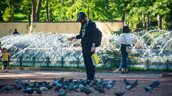 Весна в столице Грузии. Парк Ваке. Мужчина кормит голубей у фонтана - Sputnik Грузия