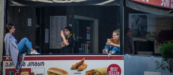 Весна в столице Грузии. Девушки сидят на прилавке закрытого кафе - Sputnik Грузия