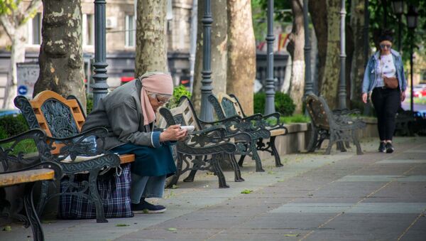 Весна в столице Грузии. Пожилая женщина сидит на лавочке и читает - Sputnik Грузия