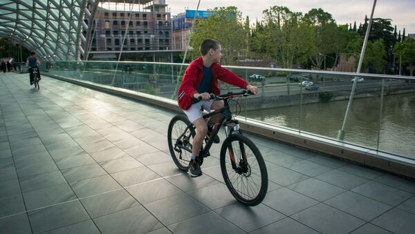 Весна в столице Грузии. Подросток катается на велосипеде по мосту Мира - Sputnik Грузия