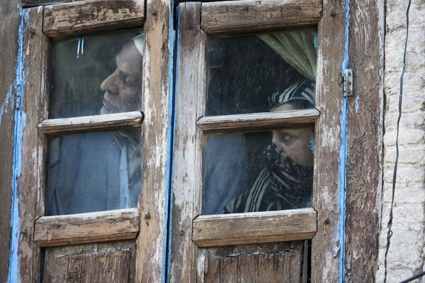 Люди смотрят из окна своего дома в Сринагаре, Индия - Sputnik Грузия
