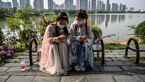 Молодые женщины в масках и в традиционных костюмах на скамейке в парке Уханя, Китай - Sputnik Грузия