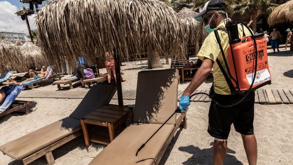 Рабочий дезинфицирует лежаки на городском пляже Алимос в пригороде Афин - Sputnik Грузия