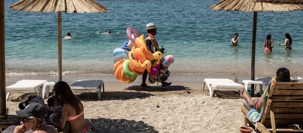 Отдыхающие и продавец игрушек на городском пляже Алимос в пригороде Афин - Sputnik Грузия