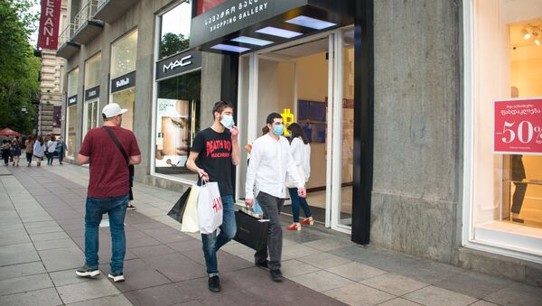 Прохожие идут по улице. Люди в масках с покупками. Снятие ограничений и открытие магазинов, кафе и ресторанов в столице Грузии - Sputnik Грузия