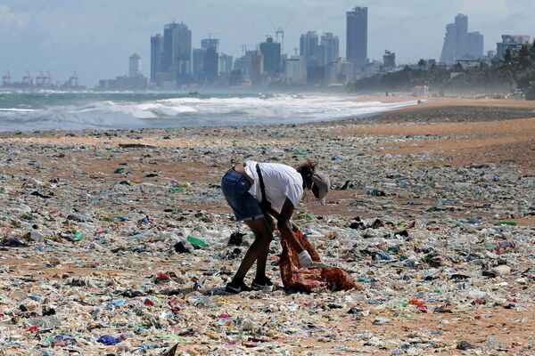 Волонтер собирает мусор на пляже. На заднем плане деловая часть города страны, где проходили мероприятия, посвященные Всемирному дню охраны окружающей среды

 - Sputnik Грузия
