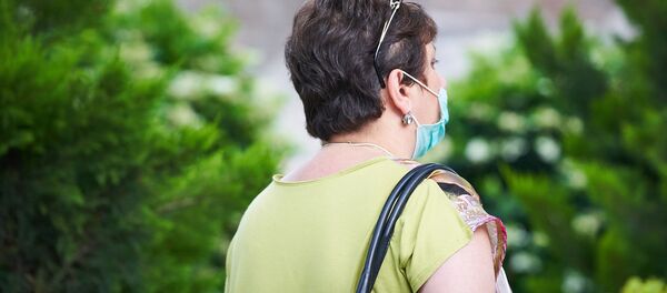 Пожилая женщина в маске идет по улице в центре города - Sputnik Грузия