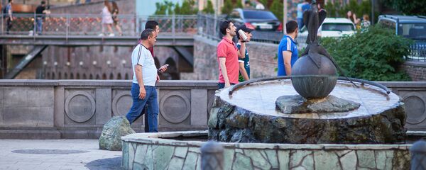 Жители города и туристы гуляют по району Абанотубани у памятника соколу и фазану Жители города и туристы гуляют по району Абанотубани у памятника соколу и фазану - Sputnik Грузия
