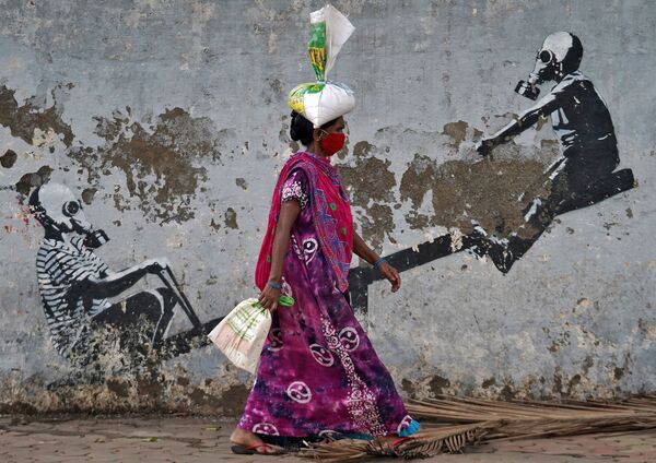 Женщина в защитной маске проходит мимо граффити в Мумбаи - Sputnik Грузия
