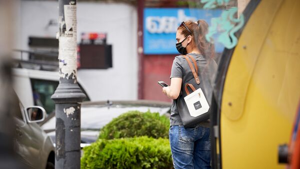 Девушка в медицинской маске со смартфоном на улице - Sputnik Грузия