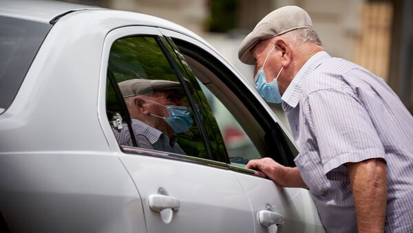 Пожилой мужчина в маске останавливает такси на улице в центре города во время пандемии коронавируса - Sputnik Грузия