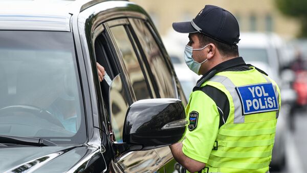 Полицейский в маске проверяет документы у водителя автомобиля в Баку - Sputnik Грузия